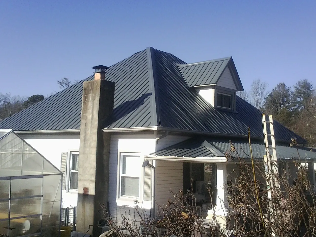 Dark blue standing seam metal roof on a white farmhouse with dormer — Slate & Tile Roof Repair by Roofing Brothers in Mcconnelsville