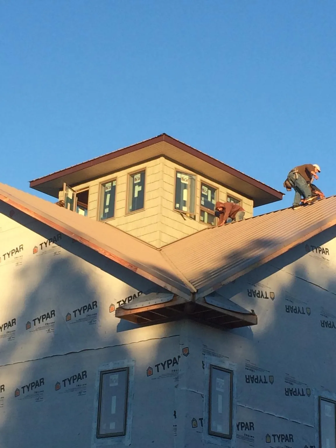 Roofers working around a rooftop cupola on a new metal roof at sunset — Roof Waterproofing in Mcconnelsville by Roofing Brothers